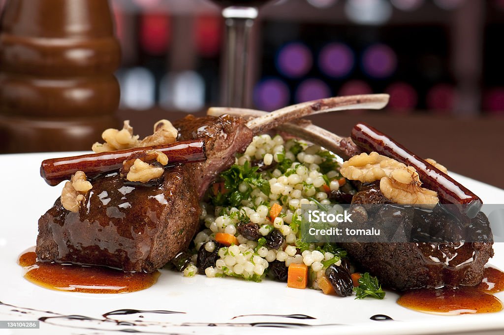 Lamb chops in restaurant Close up of lamb chops with couscous and vegetables with a sauce of caramel, pepper and spices in a restaurant setting. Lamb Chop Stock Photo