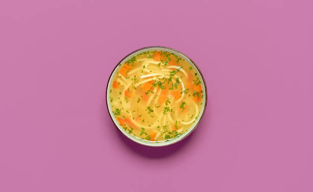 Chicken noodle soup bowl top view on a colored table. stock photo