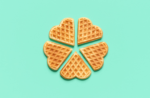 Above view with heart-shaped isolated on a green mint background. Homemade belgian waffles arranged in a circle on a green table.