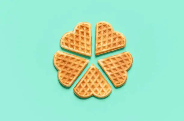 Above view with heart-shaped isolated on a green mint background. Homemade belgian waffles arranged in a circle on a green table.