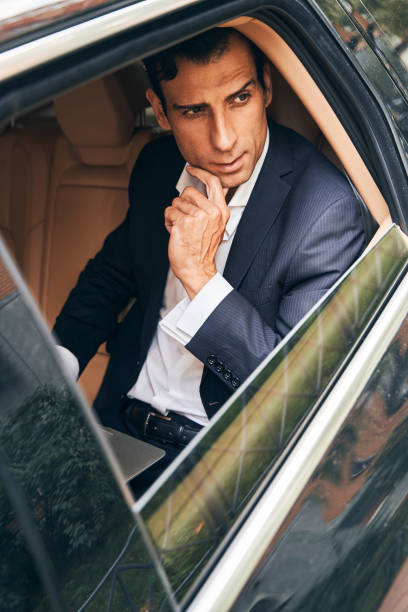 istock Man entrepreneur watching street from car back seat 1341045364
