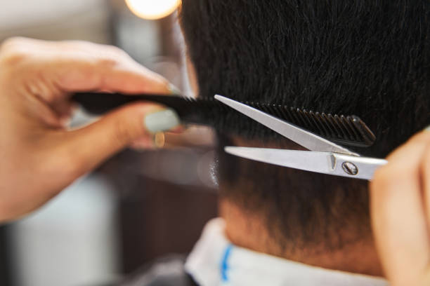 istock Scissors cutting off person hair under a comb 1341045557