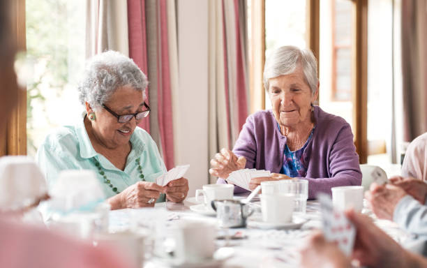 aufnahme einer gruppe älterer frauen, die in einem altersheim zusammen karten spielen - zivilist stock-fotos und bilder