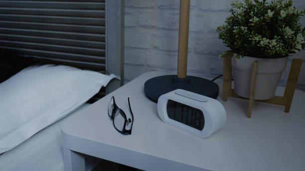 Night stand with alarm clock and eyeglasses on it