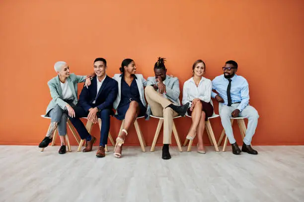 Photo of Shot of a group of businesspeople sitting against an orange background
