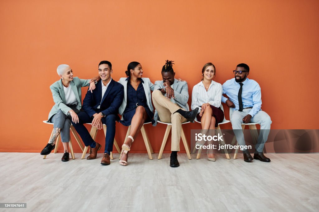 Shot of a group of businesspeople sitting against an orange background - 免版稅多族裔群種圖庫照片