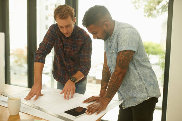 istock Shot of two young architects working on blueprints in an office 1341047723