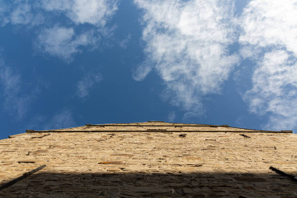 Old stone wall of house and clouds on blue sky