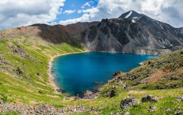 istock Panoramic alpine landscape with mountain lake in green valley 1341048955