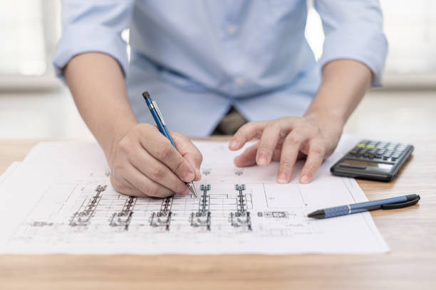 istock Engineering work concept : Close up hand a use pencil mark CAD drawing and calculator in Calculating document on the wood table 1341049899