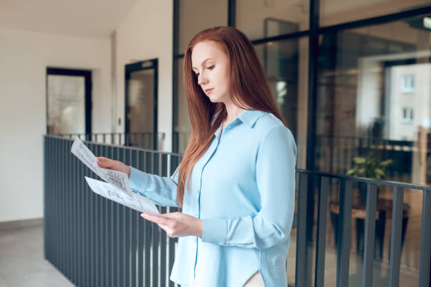 istock Attentive woman looking at blueprints indoors 1341050801