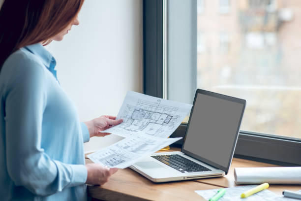 istock Focused woman reviewing construction plans on paper 1341050831