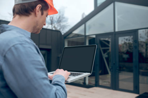 istock Man with laptop in front of smart home 1341050910
