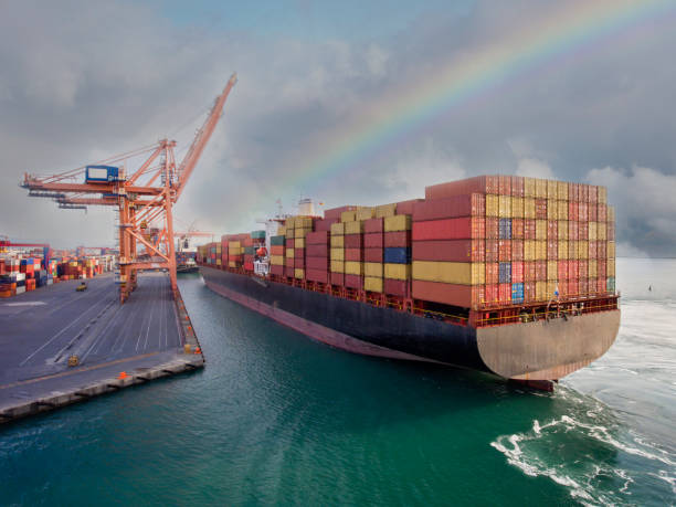 beladenes frachtcontainerschiff verlässt nach einem regnerischen tag den hafen. - singapore shipping cargo container nautical vessel stock-fotos und bilder