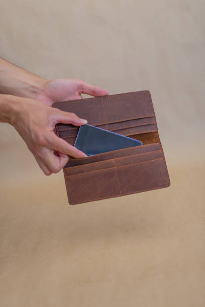 istock Person putting phone in brown leather wallet 1341058329