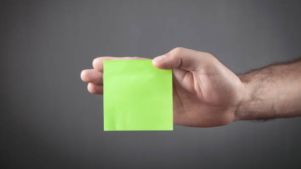 istock Male hand holding empty green sticky note. 1341065326