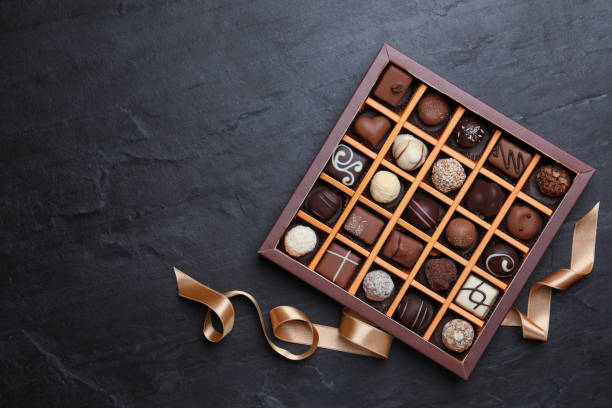 caja con deliciosos caramelos de chocolate sobre mesa negra, plana. espacio para texto - chocolate fotografías e imágenes de stock