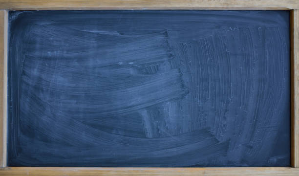 istock Background and texture of a black chalkboard smeared with chalk and roughly cleaned, with a wooden frame and space for a lot of text 1341081053