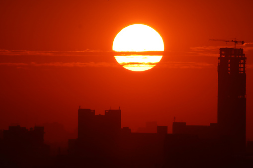 Stock photo showing air pollution, due to smog caused by car exhaust fumes and factory emissions, resulting in a dramatic orange sky at sunset with red sun indicating a high level of dust particles and water vapour.