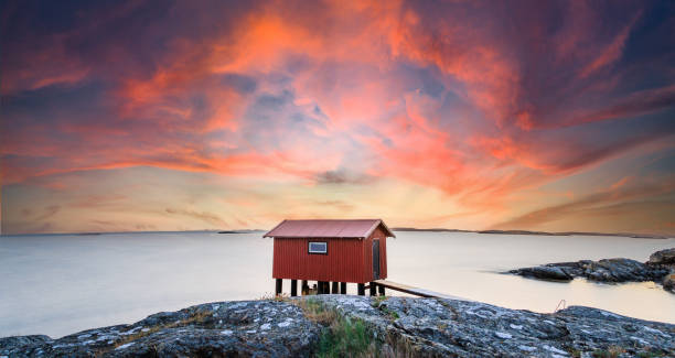 a colorful sunset of a red little fisherman's hut at the coast of sweden. Longe exposure stock photo