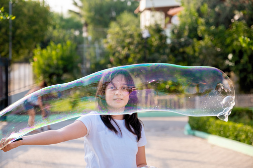 Happy carefree teenage girl blowing soap bubbles