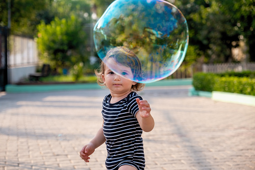 Happy carefree toddler boy blowing soap bubbles