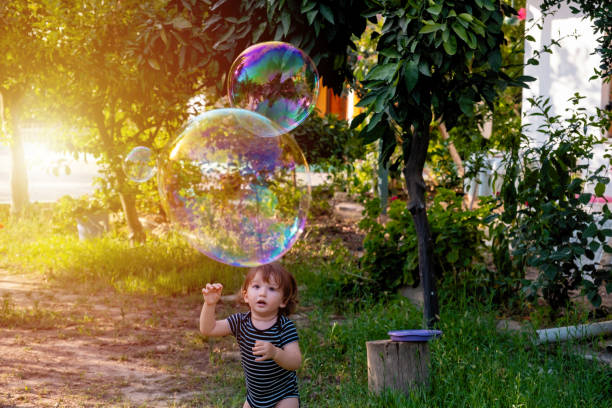 Happy carefree toddler boy blowing soap bubbles