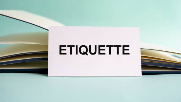 A white business card with ETIQUETTE text stands on a desk against the background of an open diary. Unfocused A white business card with ETIQUETTE text stands on a desk against the background of an open diary. Unfocused. social grace stock pictures, royalty-free photos & images