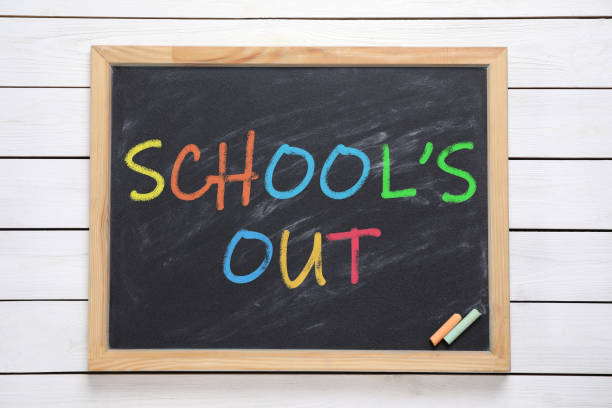 istock Chalkboard with text SCHOOL'S OUT on white wooden background, top view 1341086339