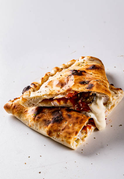 istock calzone pizza folded in half with meat, vegetables and cheese on a white background 1341087562