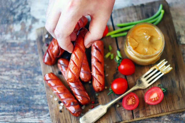 istock Sausage and fork with mustard in male hands. 1341091641