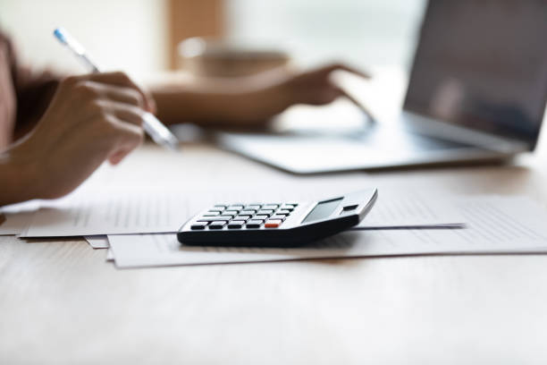close-up de trabalho de contadora feminina na mesa em laptop calculadora - financial investor - fotografias e filmes do acervo
