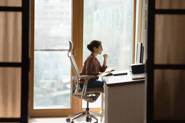 Indian female sit at workplace on ergonomic chair use pc Working at modern home office. Young mixed race female architect interior designer sit at desk on ergonomic chair doing job project on desktop pc. Millennial indian woman study at domestic workplace ergonomics stock pictures, royalty-free photos & images