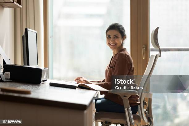 Happy Biracial Businesswoman Freelancer Sit By Computer At Comfy Workplace Stock Photo - Download Image Now