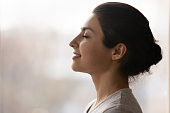 Calm millennial indian lady breath deep meditate with closed eyes