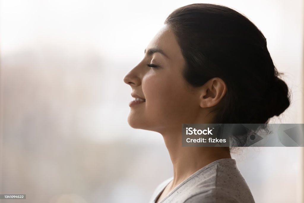 Calm millennial indian lady breath deep meditate with closed eyes Meditation. Side profile shot of happy serene young indian female face. Calm millennial ethnic lady breath deep with closed eyes meditate feel zen good harmony peace of mind practice yoga meet new day Women Stock Photo