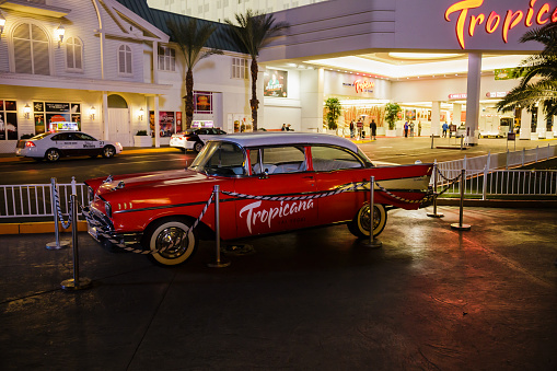 Red vintage car parked at the entrance of the Tropicana Las Vegas on the strip at night