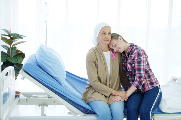 la figlia caucasica sta abbracciando la madre anziana con il velo bianco è seduta sul letto in ospedale dopo la chemioterapia perché soffre di cancro o di leucemia. - cancer chemotherapy drug baby family foto e immagini stock