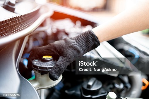 istock Hand of Technician checking brake fluid  in engine room maintenance and basic service concept of the car and brake system 1341095594