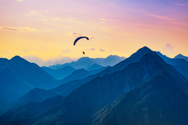 Sunset dream flight in the mountains Sunset dream flight in the mountains. Paraglider in the sky of Bordano, Italy hang glider stock pictures, royalty-free photos & images