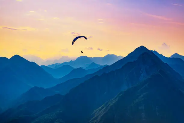 Sunset dream flight in the mountains. Paraglider in the sky of Bordano, Italy