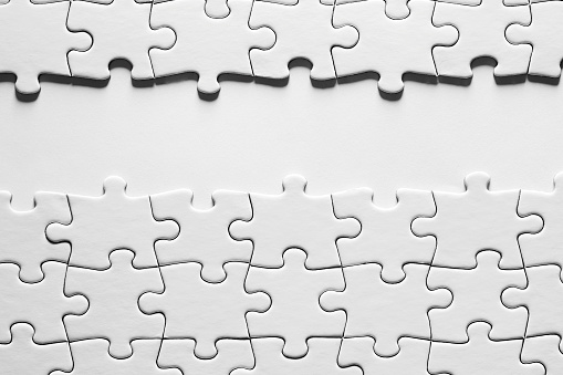 Empty white background space surrounded by white jigsaw puzzle pieces with copy space.