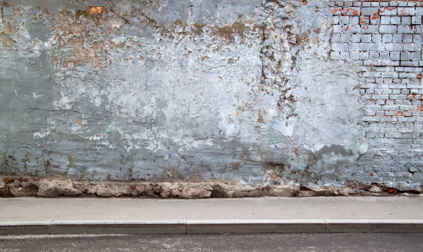 istock empty city street with wall with partially collapsed brickwork, pedestrian sidewalk and asphalt roadway. street wall background. empty grunge urban street with warehouse brick wall 1341098976