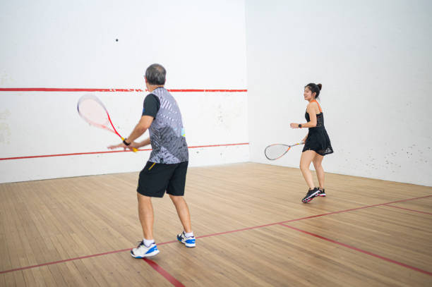asian squash coach father guiding teaching his daughter squash sport practicing together in squash court - racket ball indoors competition imagens e fotografias de stock