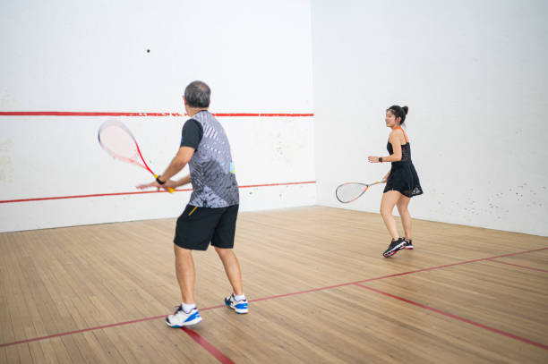 asian squash coach father guiding teaching his daughter squash sport practicing together in squash court - squash racketball sport exercising imagens e fotografias de stock