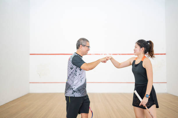 l’entraîneur de squash asiatique se cogne le poing avec son étudiante adolescente sur le court de squash après le match - racketball racket ball court photos et images de collection