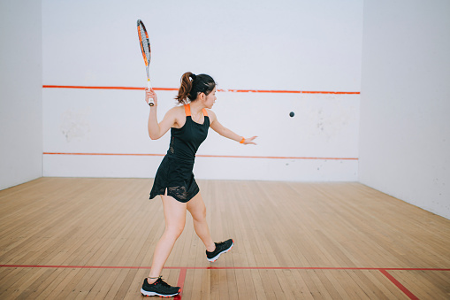 Asian chinese teenage girl practicing squash