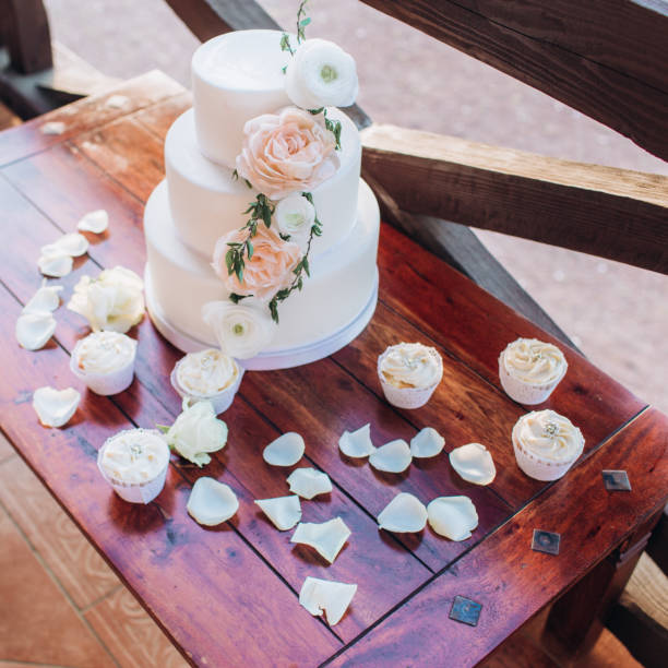 istock White wedding cake with flowers on a wooden table. 1341104311