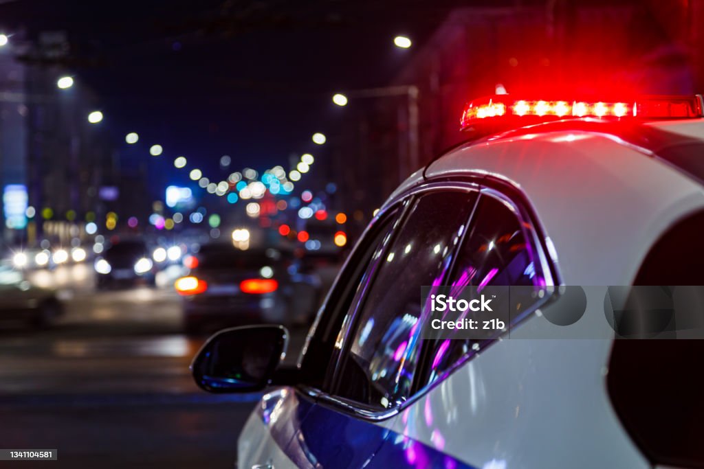 police car lights in night city with selective focus and bokeh police car lights at night in city with selective focus and blurry car traffic in the bokeh Police Force Stock Photo