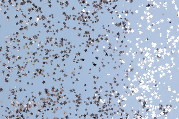 istock Bright silver colored glittering stars confetti on a blue background. 1341108291